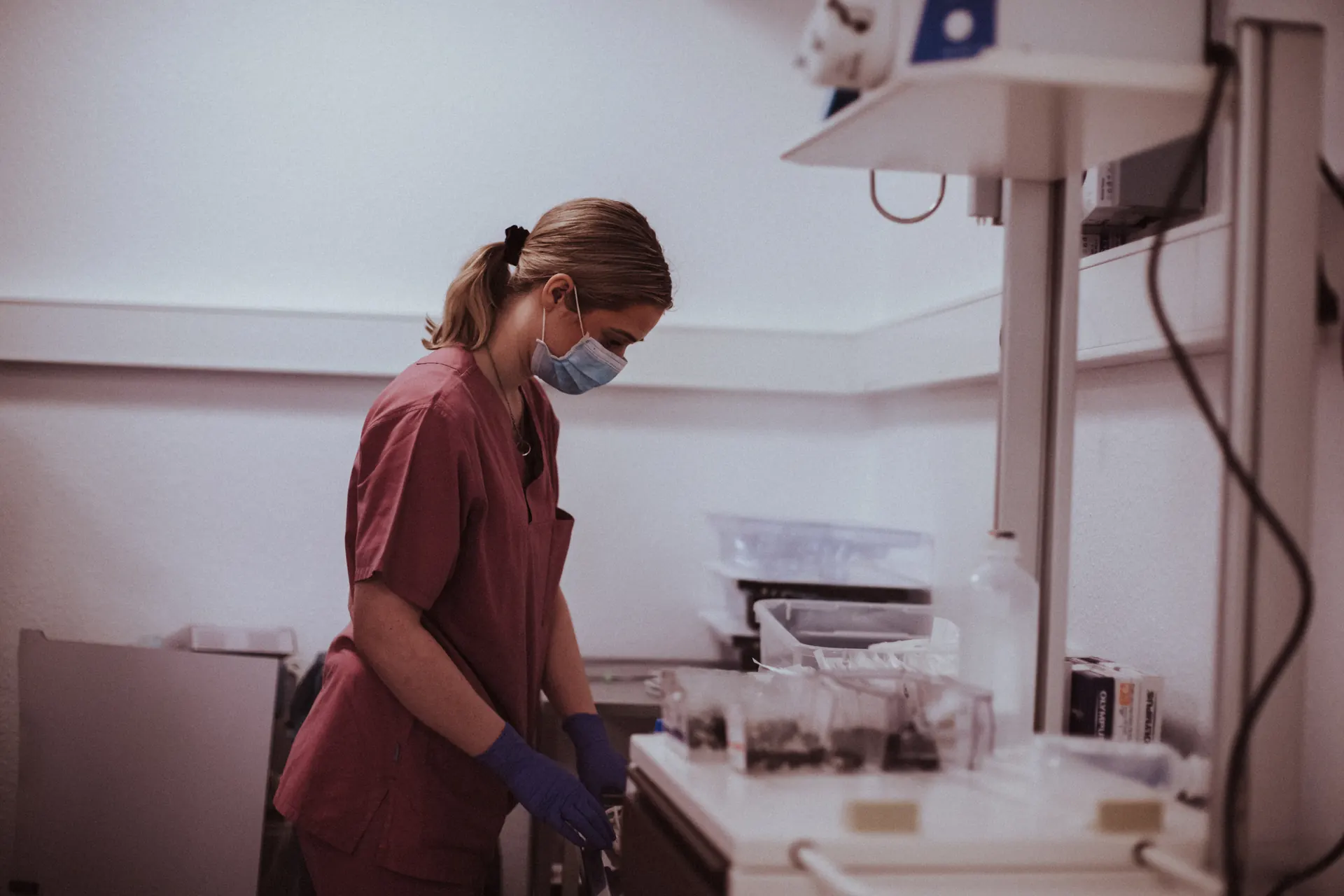 Nurse in a burgundy tunic preparing instruments in the endoscopy room