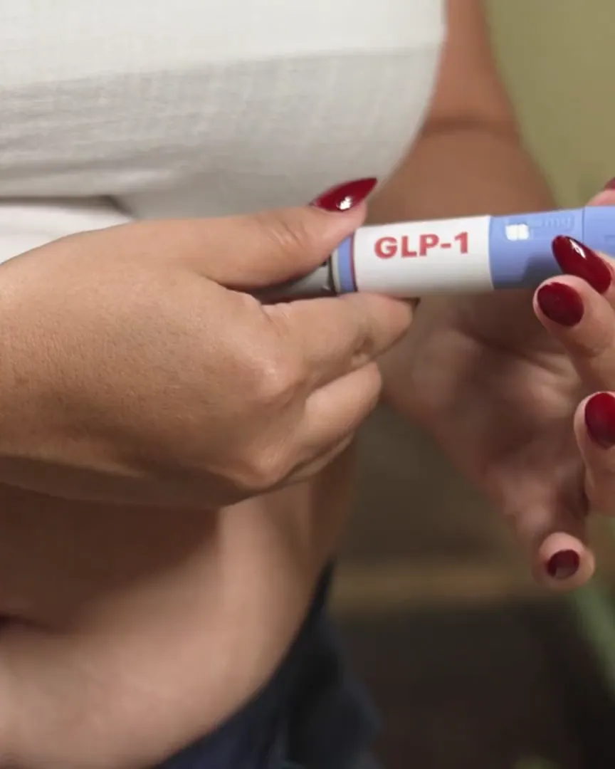 Hands holding a GLP-1 pen