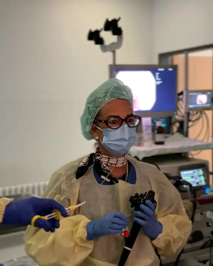 Doctor with the endoscope in front of the monitors in the examination room