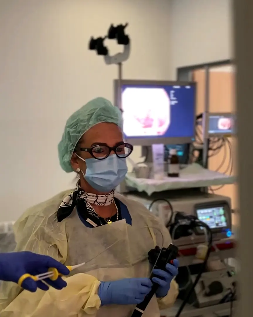 Une médecin avec l’endoscope devant les moniteurs dans la salle d’examen